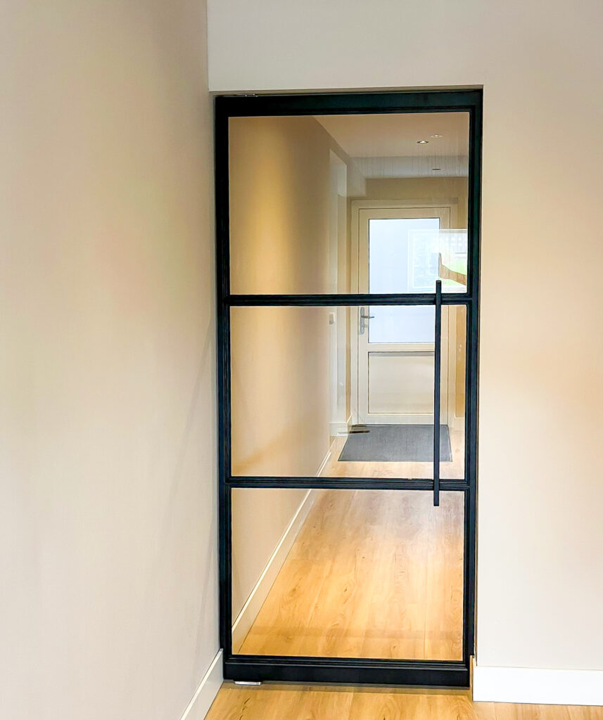 "Smale taatsdeur met glas en zwarte kozijnen"